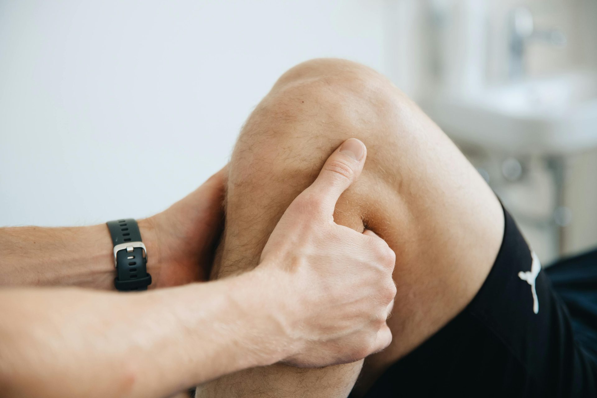 Nahaufnahme eines Physiotherapeuten, der während der Therapie das Knie eines Patienten massiert.